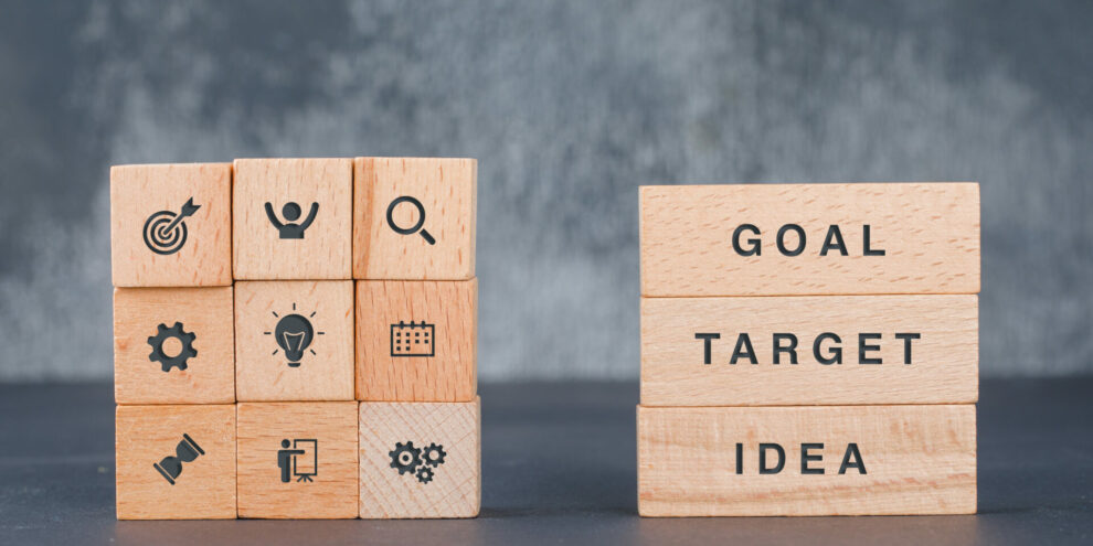 Business target concept with wooden blocks with icons on it on dark color background side view. horizontal image
