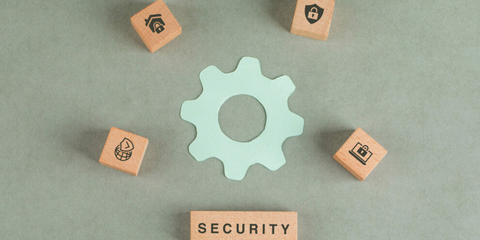 Conceptual of security with wooden blocks, paper settings icon on sage color background flat lay. horizontal image
