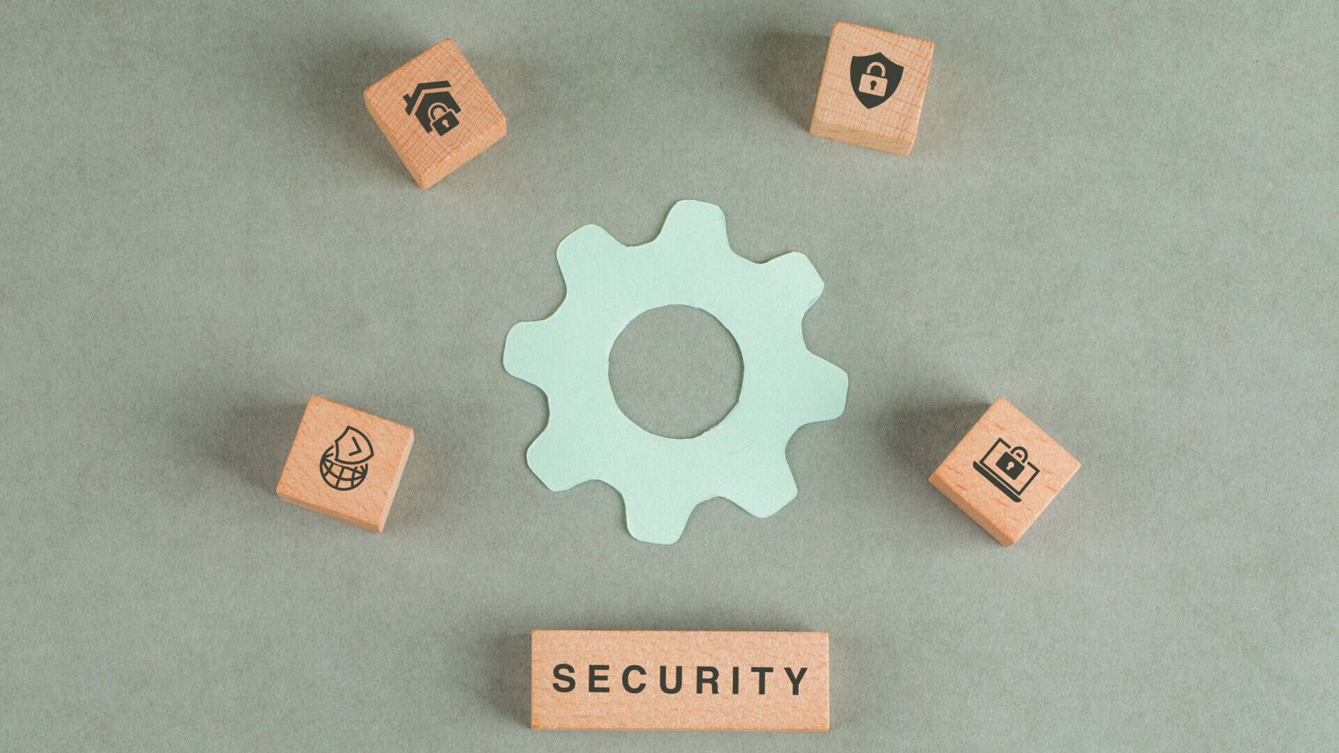 Conceptual of security with wooden blocks, paper settings icon on sage color background flat lay. horizontal image